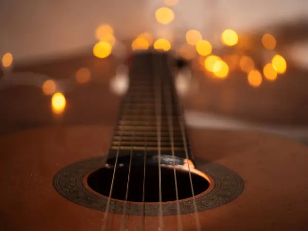 Noel ışıklarının önündeki akustik gitar seçici odak noktasını kapat