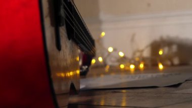 Noel ışıklarının önündeki akustik gitar seçici odak noktası.