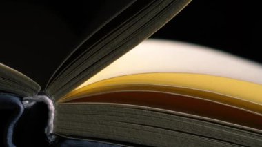 Sayfalar, mum ışığı arkaplanı olan açık bir kitap açar. 4k 'lık seçici odak noktasını kapat