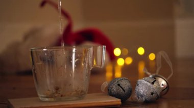 Bir bardak papatya çayı ve pırıltılı ışıklarla süslenmiş Noel süslemeleri. Arka planda, 4k 'lık seçici odak noktasını kapat.