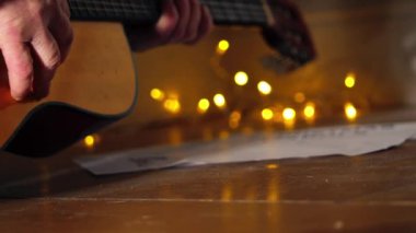 Noel ışıkları önünde akustik gitar çalmak seçici odaklanma görüntüsü verir.