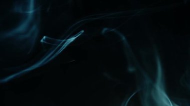 Siyah arkaplanda dönen mavi duman demetleri 4k 'lık seçici odak noktasını kapatın