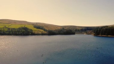 Puslu bir günde Peak District Ulusal Parkı 'ndaki göl ve tarım arazisi geniş zoom insansız hava aracı seçici odak noktası