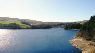 Peak District Ulusal Parkı 'ndaki göl ve tarım arazisi mavi gökyüzü manzarası geniş zoom drone hava seçici odak noktası