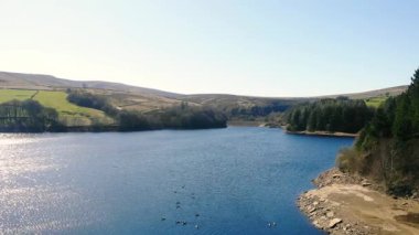Peak District Ulusal Parkı 'ndaki göl ve tarım arazisi mavi gökyüzü manzarası geniş zoom drone hava seçici odak noktası