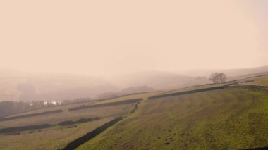 Puslu bir günde Peak District Ulusal Parkı 'ndaki kırsal tarım arazisi geniş zoom insansız hava aracı seçici odak noktası