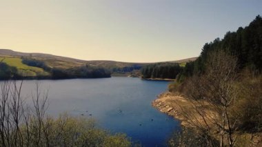 Peak District Ulusal Parkı 'ndaki göl ve tarım arazisi mavi gökyüzü manzarası geniş 4k insansız hava aracı seçici odak noktası
