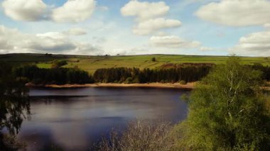 Peak District Ulusal Parkı 'ndaki göl ve tarım arazisi mavi gökyüzü manzarası geniş 4k insansız hava aracı seçici odak noktası