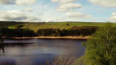 Peak District Ulusal Parkı 'ndaki göl ve tarım arazisi mavi gökyüzü manzarası geniş zoom drone hava seçici odak noktası