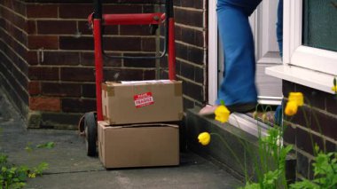 Elinde karton kutular ve tramvay taşıyan bir kadın. Evin ön kapısının önünde. 4K 'lık seçici bir fotoğraf.