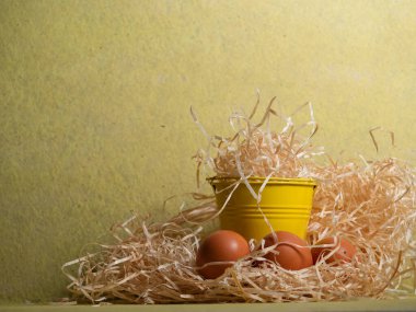 Sarı zemin üzerinde serbest yumurta ve saman yakın çekim seçici odak