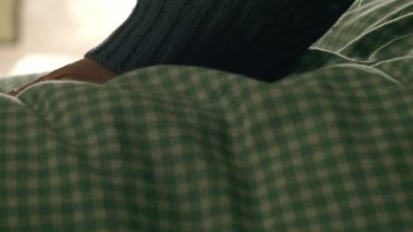 Yumuşak yorganı olan bir kadın 4K ile yatak yapıyor. Seçici odak noktasını kapat.