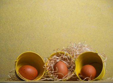 Sarı zemin üzerinde serbest yumurta ve saman yakın çekim seçici odak