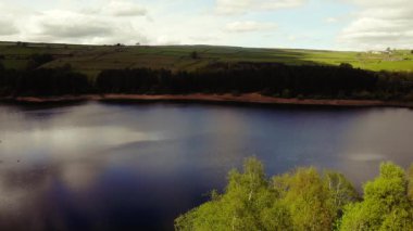 Tepe İlçesi Ulusal Parkı 'ndaki ağaçlar ve tarlalar çevresindeki göl mavi gökyüzü geniş 4k hava aracı seçici odak noktası