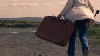 Boş otoyolda bavulla koşan bir kadın geniş açılı 4K çekim odaklı. 