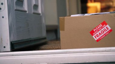 Kırılgan malların karton kutu teslimatı evin ön kapısında. 4K 'lık seçici odak noktasını kapat.