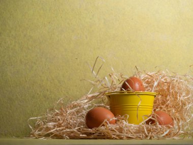 Sarı zemin üzerinde serbest yumurta ve saman yakın çekim seçici odak