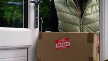 Kırılgan kutuyu eve teslim eden kadın. Orta boy 4K seçici odak noktası.