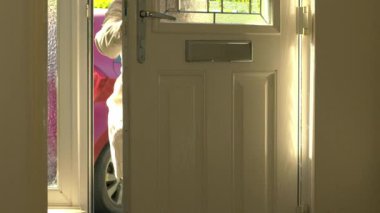 Bavullu kadın eve ön kapıdan geliyor. 4K 'lık seçici bir odaklanma. 