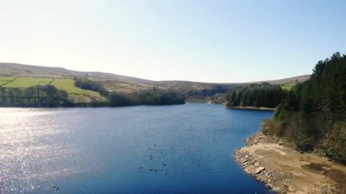 Peak District Ulusal Parkı 'ndaki göl ve tarım arazisi mavi gökyüzü manzarası geniş 4k insansız hava aracı seçici odak noktası
