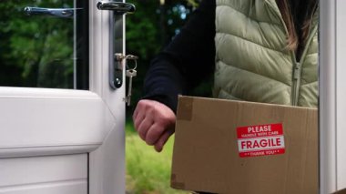 Kırılgan kutu taşıyan bir kadın 4K 'lık seçici odak noktasında kapıyı çalıyor.