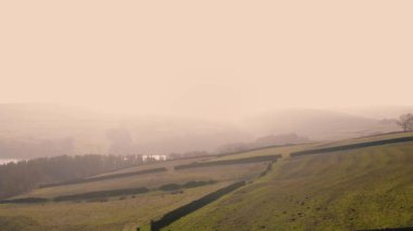 Puslu bir günde Peak District Ulusal Parkı 'ndaki kırsal tarım arazisi geniş zoom insansız hava aracı seçici odak noktası