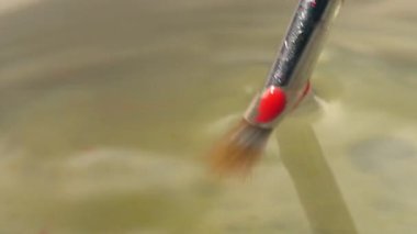 Su rengi fırçaları temizleme su kavanozuna. 4k 'lık seçici odak noktasını kapat.