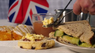 Geleneksel İngiliz çayı, çörek pıhtılaşmış kremalı ve salatalıklı sandviçler. Yakın çekim odaklı.