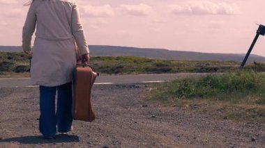Boş otoyolda bavulla yürüyen kadın geniş zoom görüntüsü seçici odak noktası 