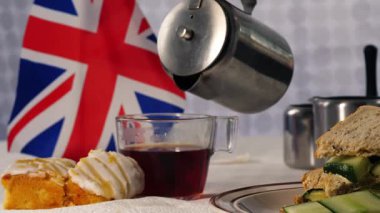 Geleneksel İngiliz çayı, pastalar ve salatalıklı sandviçler yakın çekim odaklı.