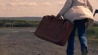 Boş otoyolda bavulla koşan kadın. Geniş zoom çekimi seçici odak noktası. 