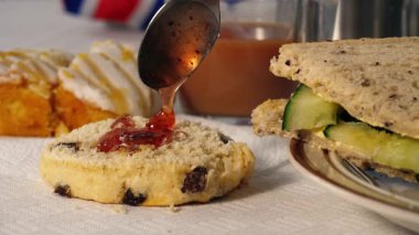 Geleneksel İngiliz çayı ve reçelli çörek ve salatalıklı sandviç 4K 'lık seçici odak noktasını kapatın.