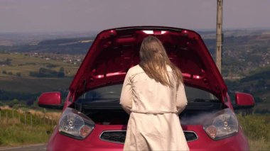 Motordan dumanı çıkan bozuk arabalı bir kadın 4K 'lık bir atış yapıyor.