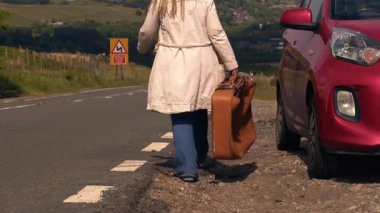 Boş otoban yolunda bavuluyla yürüyen bir kadın geniş açılı 4K çekim odaklı. 