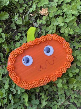 Halloween autumn pumpkin made of cardboard on the grass. Children's craft in the form of a pumpkin