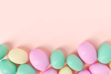 Top view of bright pink green and yellow colored Easter eggs scattered on beige background. 3d rendering