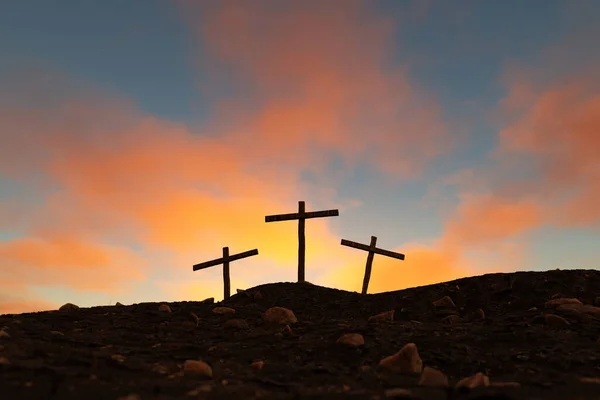 Low angle of silhouettes of crosses after crucifixion on top of rough mountains against scenic cloudy sunset sky. 3d rendering