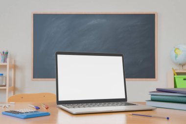Okul malzemeleriyle çevrili bir sınıf masasında dizüstü bilgisayar ve arka planda boş bir karatahta. Eğitim ve teknoloji kavramı. 3d oluşturma