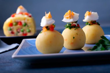 Mavi arka planda top şeklinde sunulan Causa adı verilen tipik Peru yemekleri..