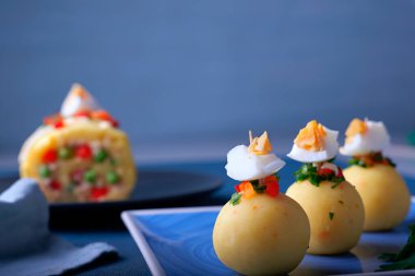 Mavi arka planda top şeklinde sunulan Causa adı verilen tipik Peru yemekleri..