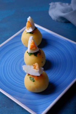 Mavi arka planda top şeklinde sunulan Causa adı verilen tipik Peru yemekleri..