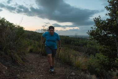 Dağlarda spor direkleri tarafından desteklenen şişman adam antrenmanları..