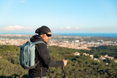 Orta yaşlı bir adam, Garraf Doğal Parkı 'nın manzaralarını incelerken bir dağın eteklerinde yürüyor..