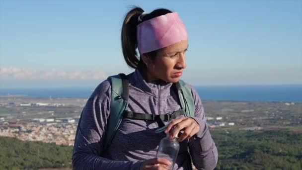 Kobieta Pijąca Wodę Szklanej Butelki Szczytu Góry Morzem Miastem Tle — Wideo stockowe
