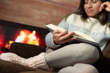 Evinin sıcaklığında kitap okuyan bir kadının yakın çekimi..