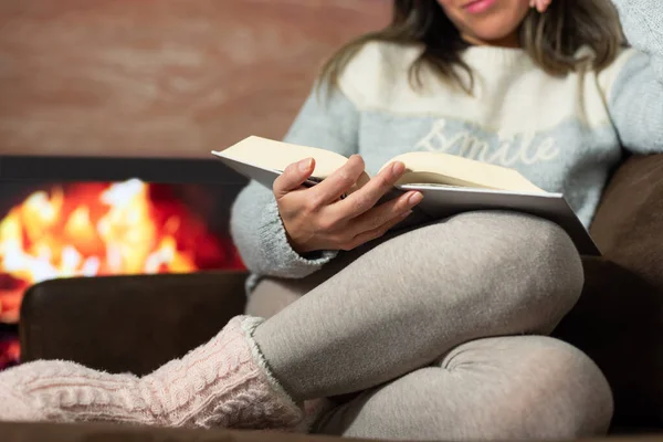 Close-up of woman reading a book in the warmth of her home.