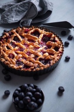 Açık mavi arkaplanda kırmızı meyve ve yaban mersinli turta.