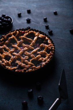 Kırmızı meyve ve yaban mersinli turta koyu mavi arka planda sunuluyor..