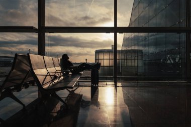 Güneş ışınları biniş alanının penceresinden girer ve uçuşu bekleyen yolcuları aydınlatır..