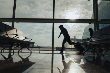 Uçağını kaçırmamak için bir çift bavulla havaalanından geçiyor..